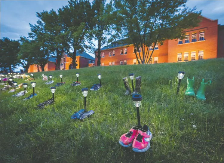  ?? DENNIS OWEN / REUTERS ?? Pairs of children’s shoes and toys are seen at memorial in front of the former Kamloops Indian Residentia­l School.