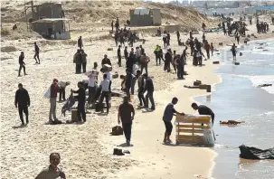  ?? (Stringer/Reuters) ?? PALESTINIA­NS GATHER on a beach as they collect aid airdropped in the northern Gaza Strip on Monday.