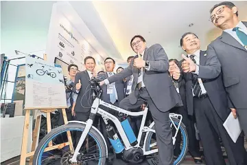  ??  ?? Abang Johari (on the bicycle) with (from right) Devamany, Wong and Dr Rundi giving their thumbs-up during a photo call prior to the press conference. — Photo by Chimon Upon