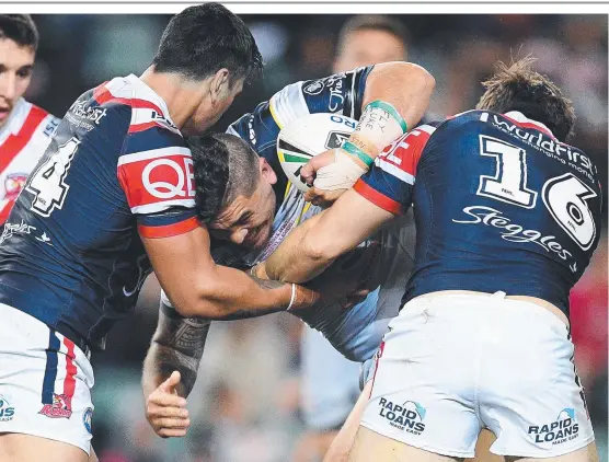  ?? LIFTING HIS GAME: Cowboys debutant Braden Uele is tackled by Zane Tetevano, ( left), and Aidan Guerra of the Roosters at Allianz Stadium on Saturday night. ??