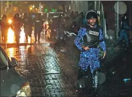 ?? Mohamed Sharuhaan Associated Press ?? A POLICE OFFICER charges toward opposition protesters early Tuesday in Male. The state of emergency declaratio­n has drawn internatio­nal condemnati­on.