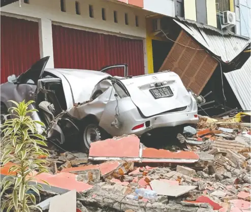  ?? ANTARA FOTO / AKBAR TADO VIA REUTERS ?? A crushed car sits in rubble after a 6.2-magnitude earthquake killed dozens of people on the Indonesian island of Sulawesi on Friday. The temblor also damaged more than 300 homes, two hotels and flattened a hospital.