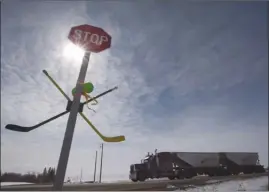  ?? The Canadian Press ?? A pair of hockey sticks are seen attached to a stop sign along Highway 5 south of Humboldt, Sask., on Friday. An accident involving a transport truck and a bus carrying the Humboldt Broncos hockey team left 16 dead and injured 13 more on April 6.