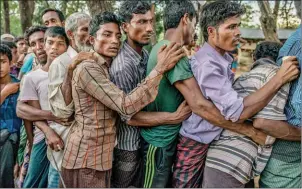  ?? TOMAS MUNITA/THE NEW YORK TIMES ?? Rohingya men line up to receive plastic tarps near a refugee camp in Cox’s Bazar, Bangladesh, on October 1.