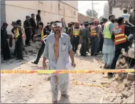  ?? PICTURE: KHURAM PARVEZ / REUTERS ?? CARNAGE: An injured man walks away after a blast near the home of Punjab Home Minister Shuja Khanzada in Attock, Pakistan, on Sunday. The bomb killed Khanzada and at least 15 others.