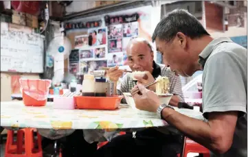  ??  ?? Two local residents eating free food at Yen noodle shop.