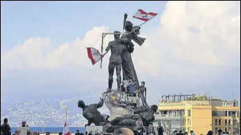  ?? REUTERS ?? Protesters fix Lebanese flags to the Martyrs' Monument at Martyrs' Square in Beirut on Sunday.