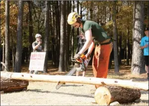  ?? The Sentinel-Record/Beth Reed ?? NEW BEGINNING: Joshua Collins, trail specialist for the Internatio­nal Mountain Bicycling Associatio­n, cuts a log instead of a ribbon, signifying the grand opening of the Northwoods Trail System Saturday at Cedar Glades Park.