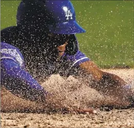  ?? Gregory Bull Associated Press ?? RAISING A CLOUD of dirt, the Dodgers’ Errol Robinson scores on a triple by Luke Raley during a six-run eighth inning against the Angels in Phoenix.