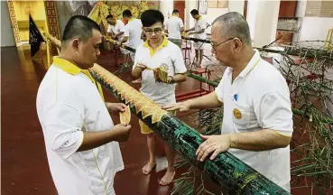  ??  ?? Team effort: Lim (right) and other volunteers pasting joss paper onto a bamboo pole at Tow Boe Keong Kew Ong Tai Tay Temple in Gat Lebuh Macallum, George Town.