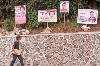  ?? Photo by Milo Brioso ?? ELECTION FEVER. A voter scans some campaign materials posted in a retaining wall. Comelec continue to remind barangay and SK candidates to observe posting of campaign materials in common poster areas.