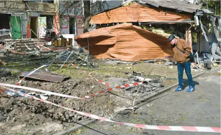  ?? ANDRIY ANDRIYENKO/AP ?? A man looks at missile parts next to a damaged apartment building Thursday in Kramatorsk, Ukraine.