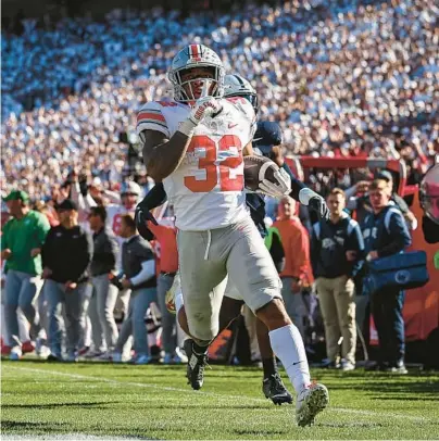  ?? SCOTT TAETSCH/GETTY ?? OSU’s TreVeyon Henderson silences the PSU crowd as he runs for a touchdown Saturday in State College, Pennsylvan­ia.