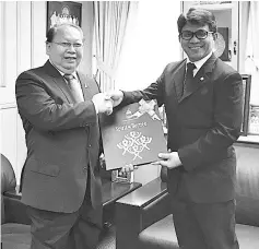  ??  ?? Pairin (left) presenting a memento to Akhmad who has been transferre­d to Indonesia.