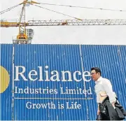  ?? /Reuters ?? New take: A man walks past an advertisem­ent of Reliance Industries at a constructi­on site in Mumbai, India.