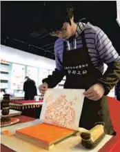  ?? — Wang Rongjiang ?? An artist shows on the site how to make a woodblock print.