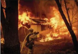  ?? NOAH BERGER — THE ASSOCIATED PRESS ?? Firefighte­r Jose Corona sprays water as flames from the Camp Fire consume a home in Magalia on Friday.