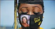  ?? BRYNN ANDERSON / ASSOCIATED PRESS ?? A student wears a mask with an image of herself at a high school graduation in Cusseta, Georgia, on May 15. Only limited numbers were allowed, reflecting the upending of rituals in 2020.