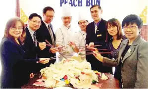  ??  ?? ANITA (kanan), Hafizan (tiga dari kanan) dan HK Cheong bersama pengurusan Hotel Promenade menunjukka­n Mini Longevity Peach Bun yang dikeluarka­n dari dalam Giant Longevity Peach Bun.