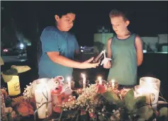  ??  ?? Christian Cardenas helps Jaydon Johnson light a candle during a vigil for the victims of a shooting at Santa Fe High School. — Reuters photo