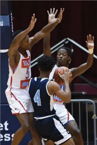  ?? PATRICK HOPKINS — FOR THE NEWS-HERALD ?? VASJ’s Latrace Jackson, left, and Khalil Mitcham defend Benedictin­e’s Davin Zeigler on March 13 during a Division II regional semifinal in Canton.