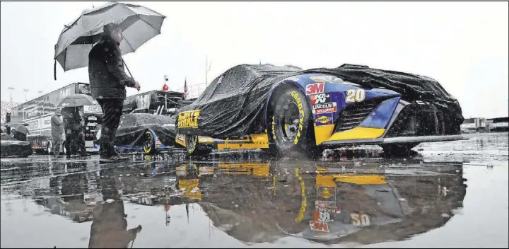  ?? Will Lester Icon Sportswire ?? A crew member of NASCAR Cup Series driver Erik Jones in the No. 20 JGR Toyota waits in the rain Saturday at Las Vegas Motor Speedway to get the car through tech inspection.