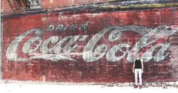  ?? Photo by Jake Mercer ?? Owner of the 219 Antique Store Stephen Bagley stands alongside the vintage Coca-Cola sign that was found as constructi­on for a new Sheetz store began.