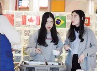  ?? NEWS PHOTO EMMA BENNETT ?? Arum Oh and Jiin Lee serve bulgogi — a Korean barbecue beef dish — during an internatio­nal food fair held by Medicine Hat College students celebratin­g Internatio­nal Education Week.