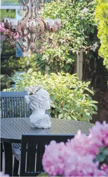  ??  ?? An outdoor chandelier from Chintz and Co. hangs over a patio table on the street side of the house, near a white wooden pergola Jim made. “We often have supper here as it’s completely protected,” Jim says. It is surrounded by rhodos and Nelly Moser clematis.