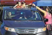  ?? Myung J. Chun Los Angeles Times ?? JENNIFER OLIVAS hands out treats to 6- year- old twins Loucia Ramirez, left, and Adriana Ramirez during the Monterey Park Candy Caravan.