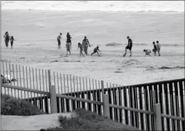  ?? ASSOCIATED PRESS ?? IN THIS JULY 20, 2018, FILE PHOTO, PEOPLE WALK AND FISH on the beach and children play soccer on the Mexico side of the border wall as seen from the Friendship Park in San Diego. A congressio­nal watchdog agency says the Trump administra­tion’s plan to...