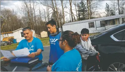  ?? (AP/Jacquelyn Martin) ?? Prisi Hernandez (left) and Laura Hernandez, both with the organizati­on Siembra NC, help Nery Ocampo, 19, (center) to register to vote as Irvin Bahena, 10, stops March 11 to watch from his bicycle in a largely Latino trailer community in Burlington, N.C. It will be Ocampo’s first time voting. “I didn’t have time to register before,” says Ocampo, “it’s important for Latinos who can to vote, in order to help those who can’t.”