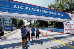  ?? CURTIS COMPTON / CCOMPTON@AJC.COM 2014 ?? Race officials with the Atlanta Track Club go over final preparatio­ns at the finish line for the AJC Peachtree Road Race at Piedmont Park in 2014. Tens of thousands of runners will gather Wednesday morning at Lenox Square in Buckhead to start this...