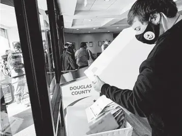  ?? NATI HARNIK/AP ?? An election commission member collects early ballots from a drop box Saturday in Omaha, Nebraska.