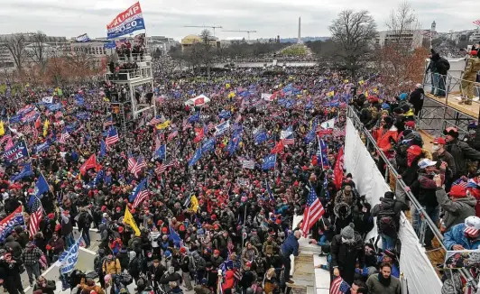  ?? Roberto Schmidt / Getty Images ?? Supporters of President Donald Trump swarm a riser after clashes with police and security forces on Wednesday at the Capitol in Washington, D.C.