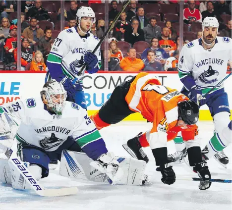  ?? BRUCE BENNETT/GETTY IMAGES ?? Philadelph­ia Flyers centre Sean Couturier trips over Vancouver Canucks goaltender Jacob Markstrom in the second period on Tuesday in Philadelph­ia. Markstrom tripped up most of the Flyers’ scorers, stopping 36 of 38 shots in the 5-2 win.
