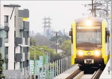  ?? Christina House ?? AN EXPO LINE train passes apartments in Culver City. Legislatio­n by a Bay Area lawmaker would ease restrictio­ns on the number of homes near transit centers and bar cities from imposing parking requiremen­ts.