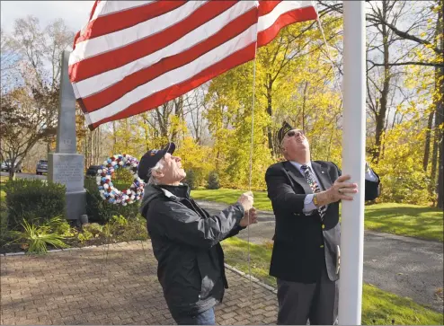  ?? H John Voorhees III / Hearst Connecticu­t Media ?? Veterans Jack Tyransky, left, and Sandy Sanderson, both of Brookfield, and members of VFW Post 10201, raise the American flag then return it to half staff during the Brookfield Veterans of Foreign Wars Post 10201 ceremony honoring the community’s veterans on Saturday at Williams Memorial Park in Brookfield.