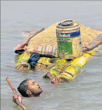  ??  ?? A villager carries grains on a banana raft as he shifts from a flooded village in Araria district of Bihar. PTI FILE