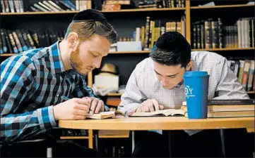  ?? LUIS ANDRES HENAO/AP ?? Yeshiva University students Aaron Heideman, left, and Marc Shapiro study at the university’s library Thursday in New York. Heideman said the president’s order will help his friends at secular universiti­es who have run into problems.