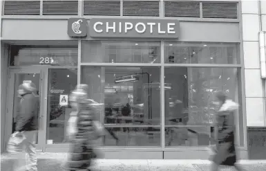  ?? ANDREW RENNEISEN/GETTY 2016 ?? People walk by a Chipotle restaurant in New York City. The fast-food chain cited higher labor costs for a 4% hike in the price of its menu items last summer and is looking for other ways to boost profitabil­ity. That includes higher prices for delivery.