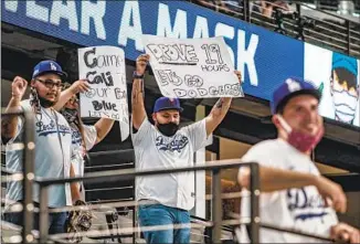  ?? L. A. BOOSTERS ?? try to get players’ attention during batting practice before Game 3 in Arlington, Texas. The COVID- 19 pandemic prevented fans from attending any MLB games until last week.