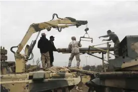  ??  ?? MOSUL: Iraqi Army soldiers load rockets into a multi-barrel rocket launcher during fight against Islamic State militants to regain control of Mosul University. —AP