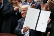  ?? THE ASSOCIATED PRESS ?? President Donald Trump holds up a signed executive order aimed at easing an IRS rule limiting political activity for churches, Thursday, May 4, 2017, in the Rose Garden of the White House in Washington.