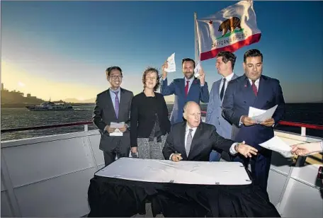  ?? Photograph­s by Gina Ferazzi Los Angeles Times ?? ABOARD a hybrid-electric ferry Thursday in the San Francisco Bay, Gov. Jerry Brown signs a package of bills to combat climate change.