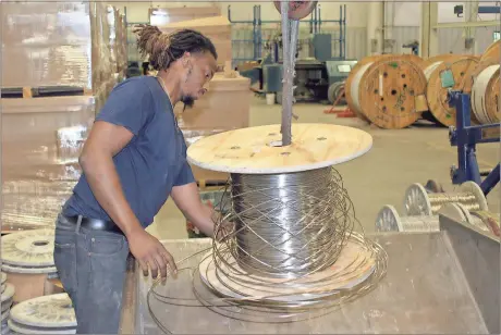  ?? Doug Walker / Rome News-Tribune ?? Demarcus Windom unwinds a spool of cable that will ultimately be scrapped from the Brugg Cable plant. Suhner Manufactur­ing will take over the Brugg plant July 1. Suhner will add 28 people to its workforce during a job fair Monday at the Goodwill Career Center on Hicks Drive.