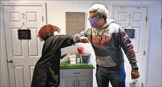  ?? HYOSUB SHIN / HYOSUB.SHIN@AJC.COM ?? Nekesa Smith and AJC reporter Ernie Suggs bump elbows after she gave him advice about his hair and growing an Afro at her shop in College Park.