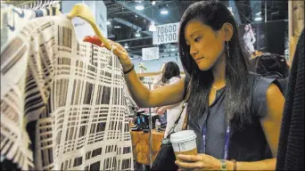  ?? MARTIN S. FUENTES/LAS VEGAS REVIEW-JOURNAL ?? So Kim looks through the Freeway’s clothing during the MAGIC trade show Aug. 15 inside the Las Vegas Convention Center. The twice-yearly event starts Tuesday.