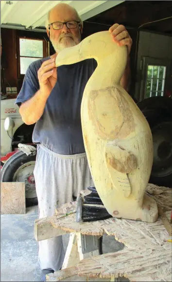  ?? (Special to the Democrat-Gazette/Dean Hurliman) ?? With his garage door open for light, Dean Hurliman wears comfy clothing including foam shoes while shaping his “Great Auk” in Burlington, Iowa.