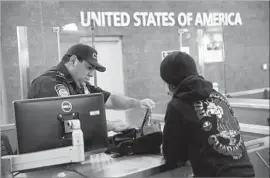  ?? John Moore Getty Images ?? A CUSTOMS and Border Protection officer at San Ysidro checks a backpack. A cafeteria worker there was convicted of being involved in a smuggling operation.